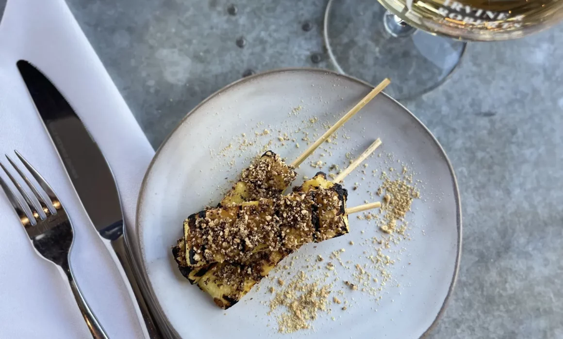 Small plate with skewers and a glass of white wine